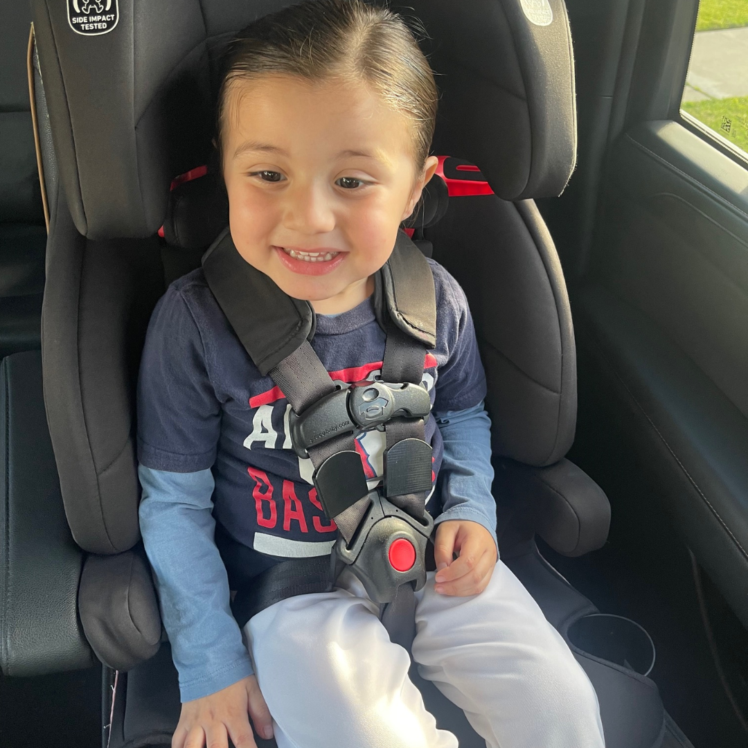 A toddler in a five-point car seat with strap detangler installed.