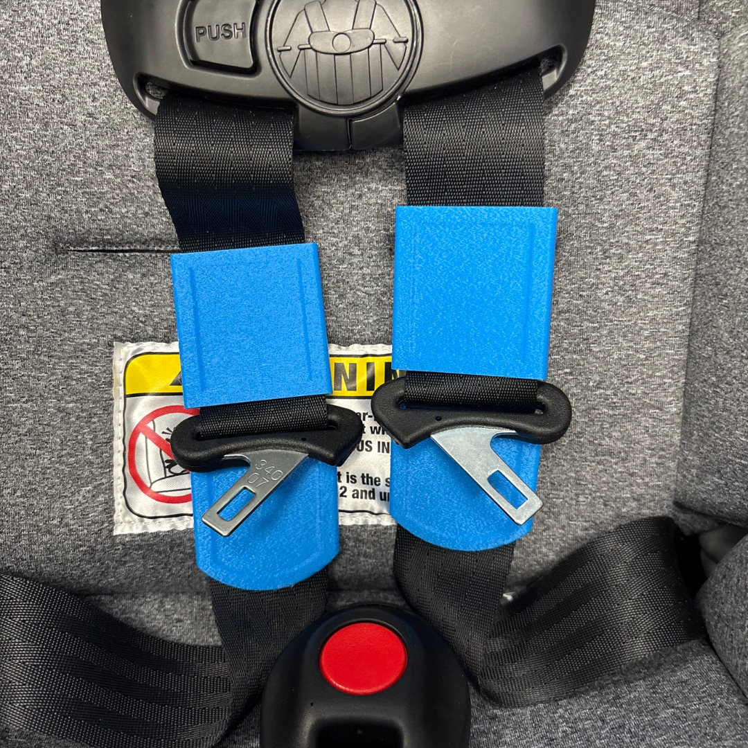 Close-up photo of bright blue Buckle Buddeez device holding car seat straps flat alongside the buckle.